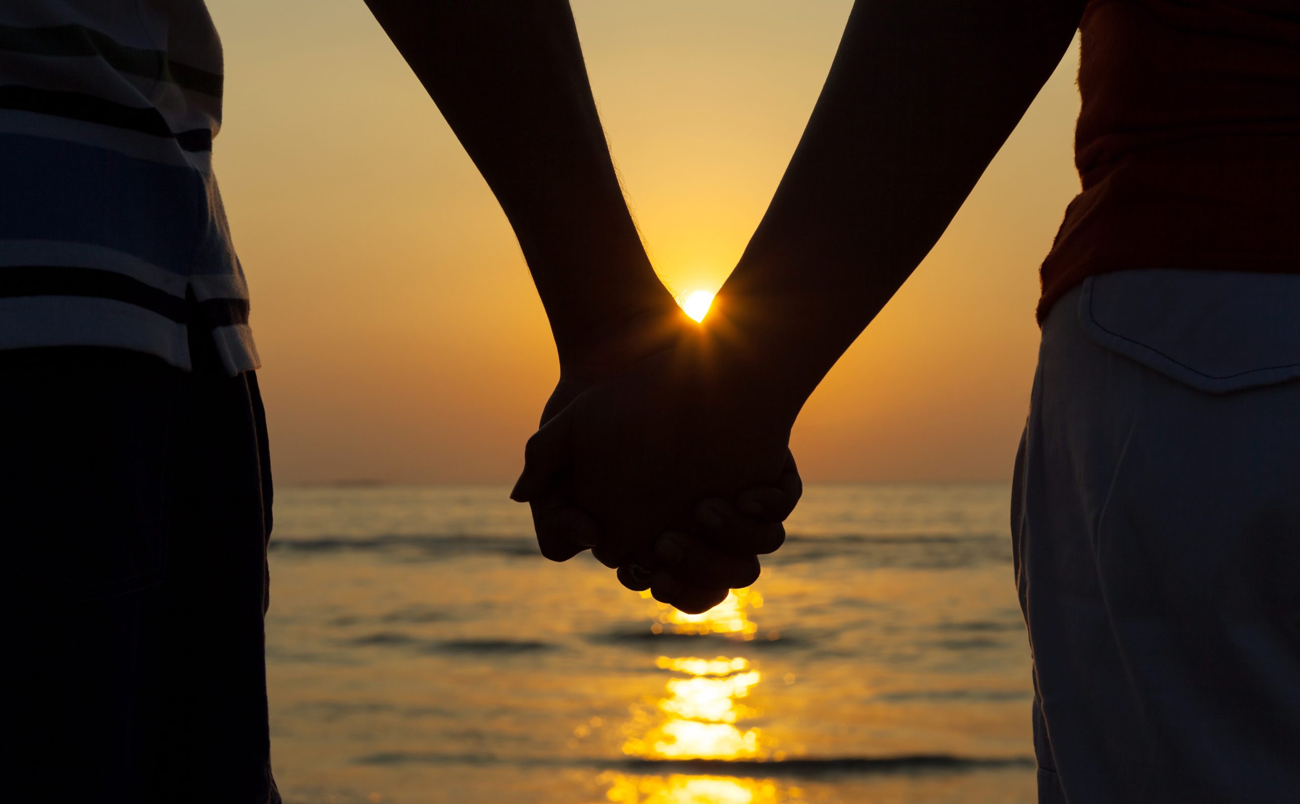 Silhouettes couples holding hands on sunset. Eleos Counselling , compassionate couples therapy in West Sussex a picture of a couple holding hands at sunset