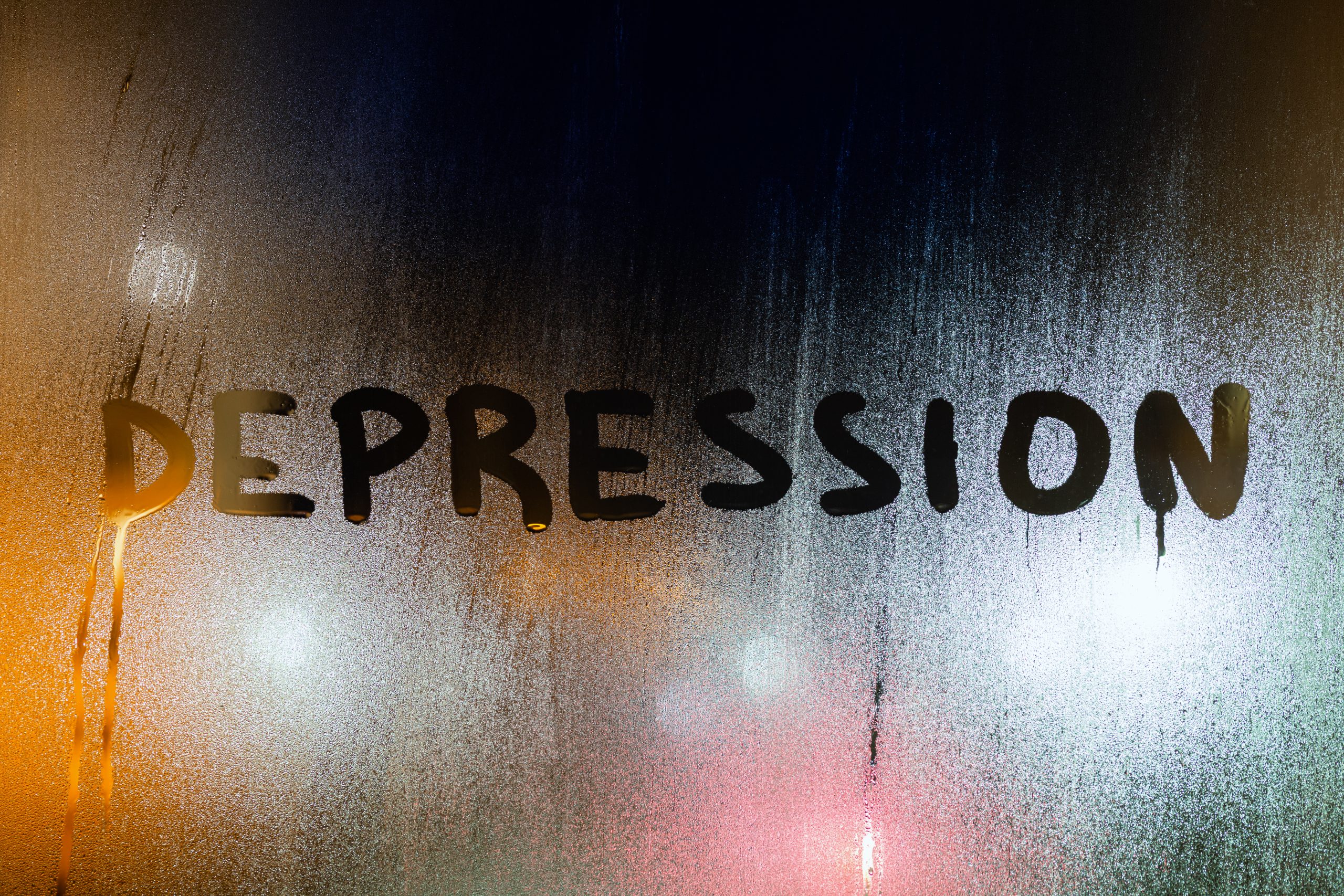 the word depression written by finger on night wet glass with blurred lights in background peaceful countryside path in West Sussex, symbolising a journey toward clarity and emotional healing—ideal for those seeking counselling psychotherapy for depression West Sussex.