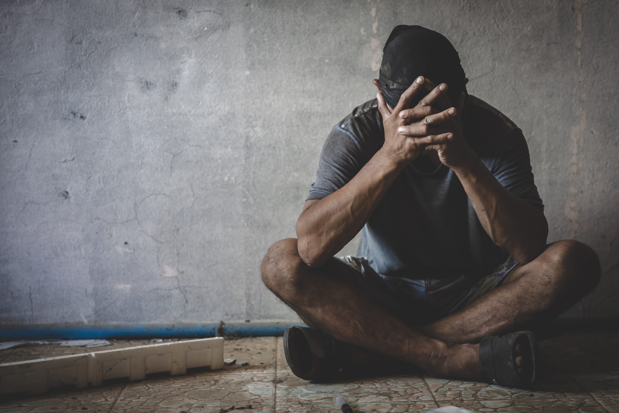 Depressed man sitting in abandoned building. Sad man crying. Dra Substance misuse counselling, psychotherapy in West Sussex.